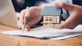 close-up-real-estate-agent-with-house-model-hand-putting-sign